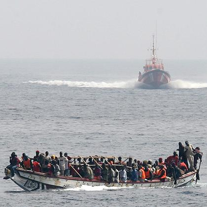 Photo: Cayuco approached by a spanish Salvamar vessel (June 25, 2008) by Noborder Network. CC-BY-2.0 (via Wikimedia).