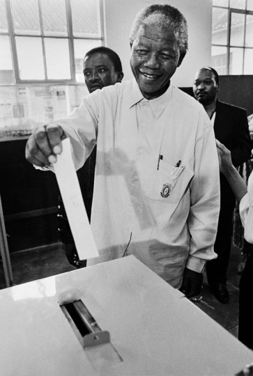 Photo: This is the official photo of Mandela casting his vote in the 1994 elections. It was the first time Mandela had voted in his life. It was taken at Ohlange School, Inanda, Durban (April 1, 1994) by Paul Weinberg/CC-BY-SA-3.0 (via Wikimedia).