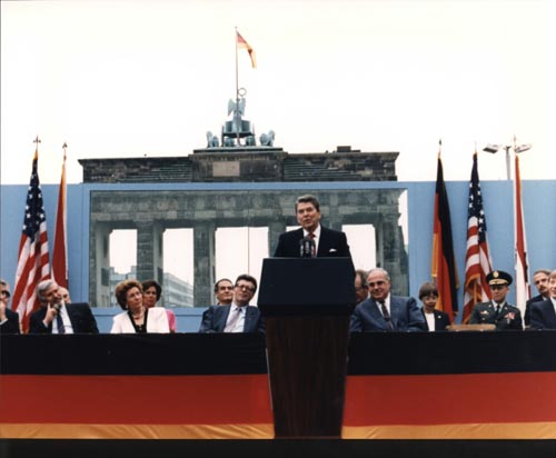 Photo: Ronald Reagan speaking in front of the Brandenburg Gate and the Berlin Wall (June 12, 1987) by Ronald Reagan Presidential Library. Public domain (via Wikimedia).